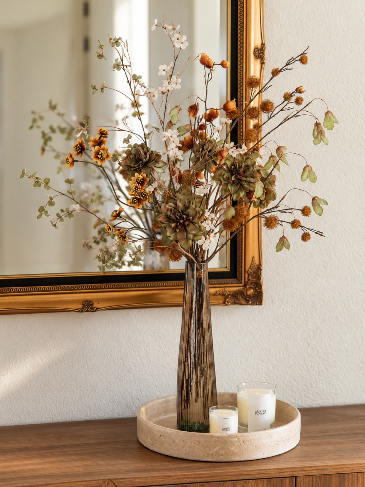 Zijden bloemen boeket Fina in een glazen vaas op een houten dressoir, met groene en bruine kunstbloemen voor een warm herfstinterieur.