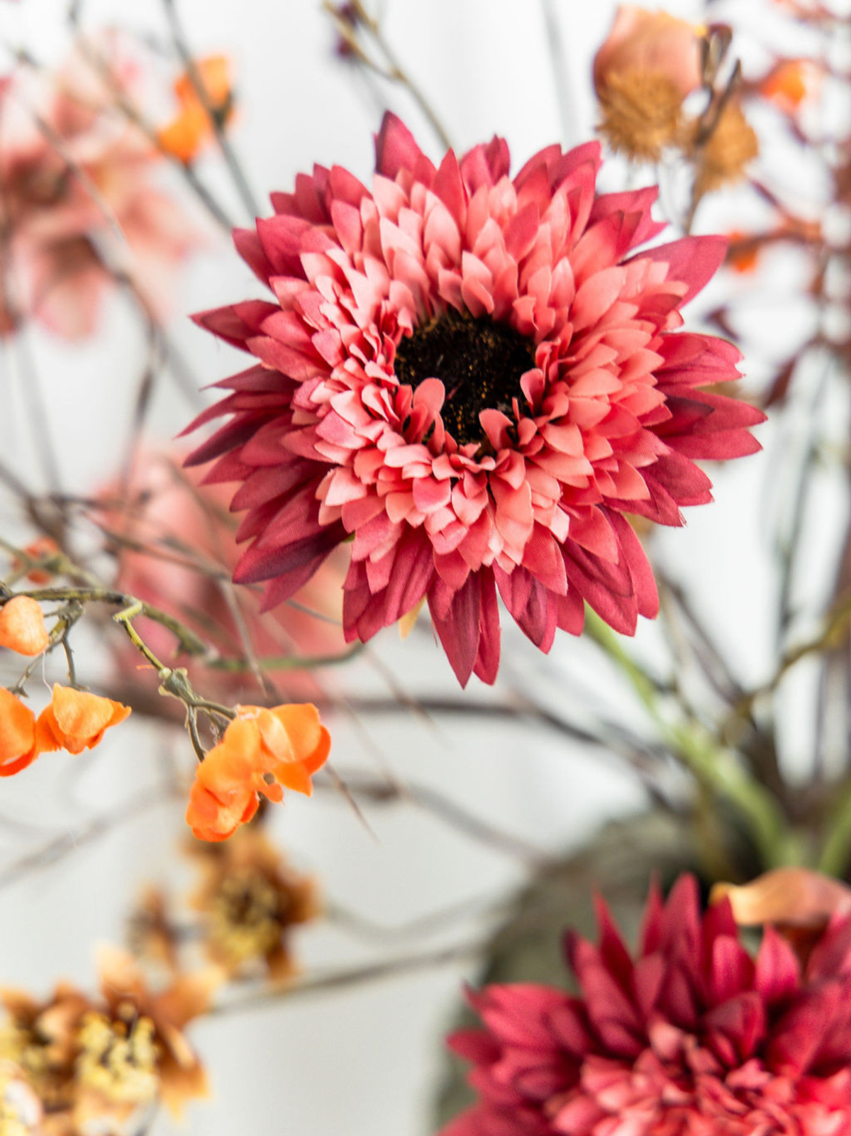 Close-up van roze gerbera en oranje kunstbloemen in zijden boeket Amelie, met realistische bloemdetails en warme herfstkleuren.
