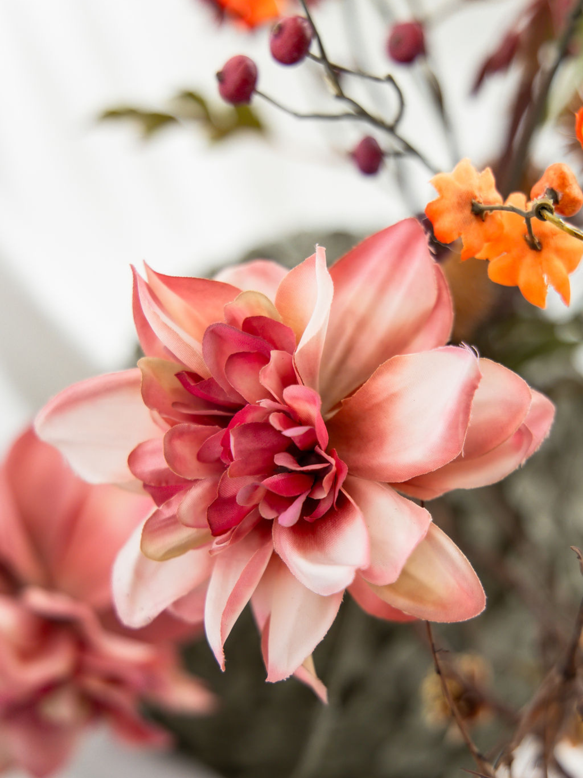 Detail van roze zijden bloem met oranje cherrytak in kunstboeket Amelie, een kleurrijk herfstboeket met natuurlijke uitstraling.