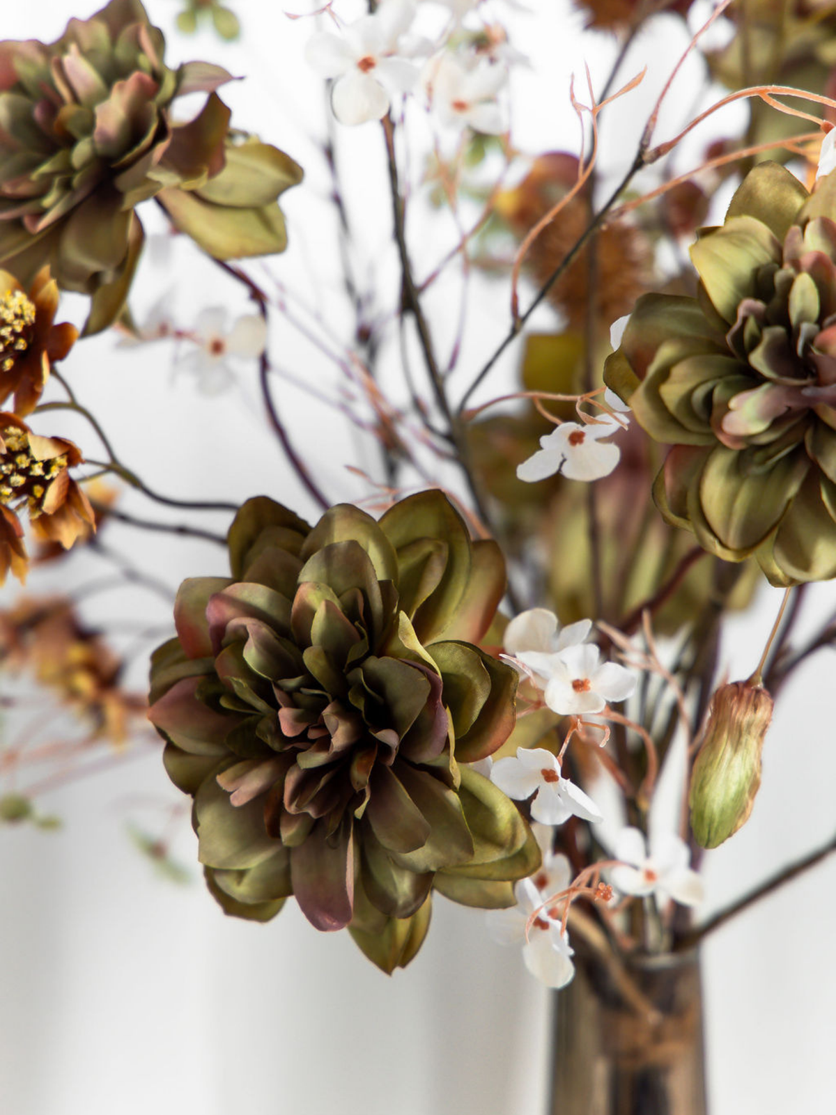 Close-up van groene kunstbloemen met crèmekleurige zijden bloesem en fijne herfsttakken in boeket Fina.