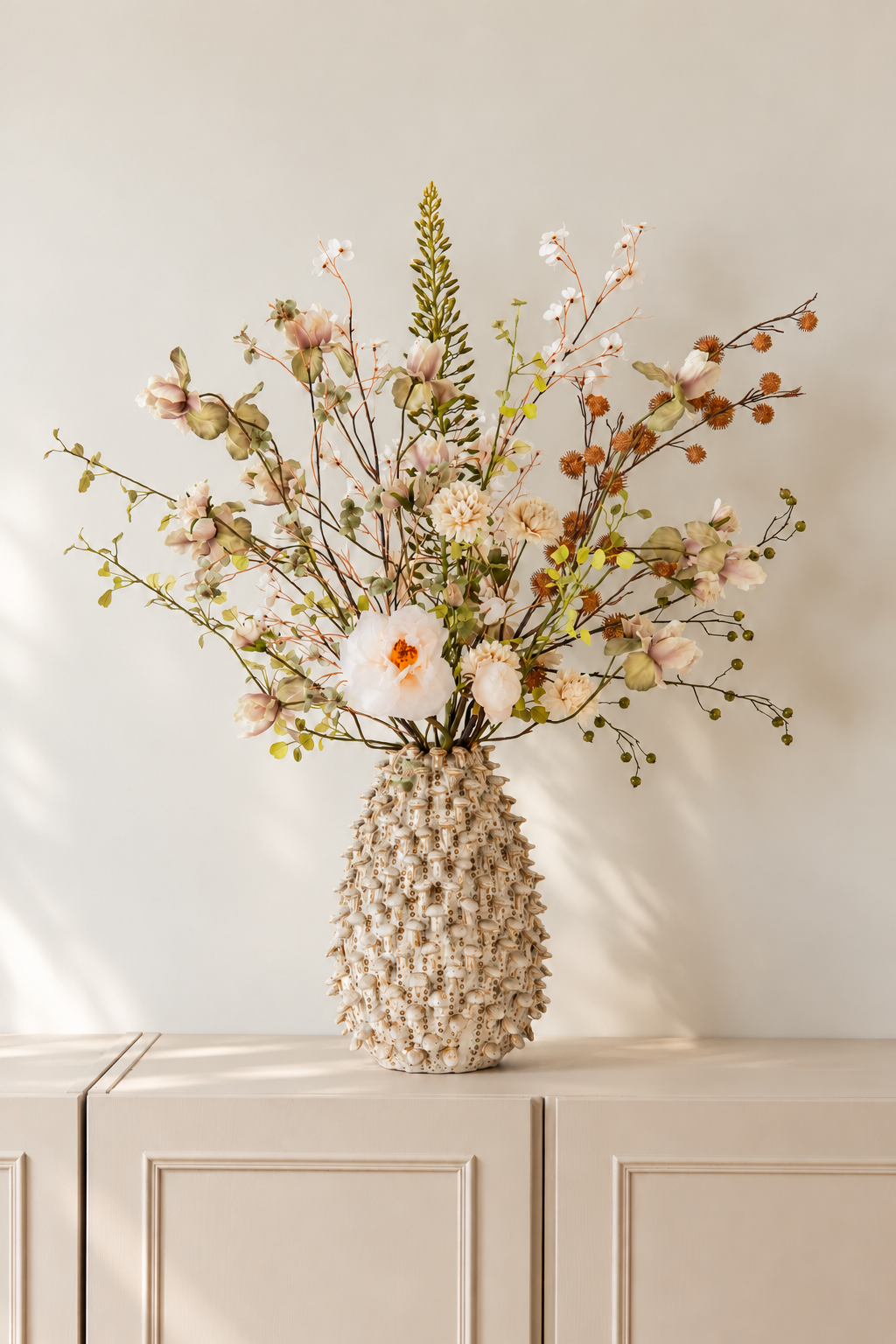 Groen en crème zijden bloemen boeket Suus in een beige vaas op een dressoir, passend bij een rustig Japandi interieur.